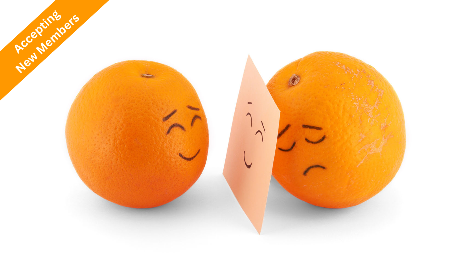 Two oranges. One has a smiley face drawn on it and the other has a sad face on it while hiding behind a smiley face on a piece of paper.
